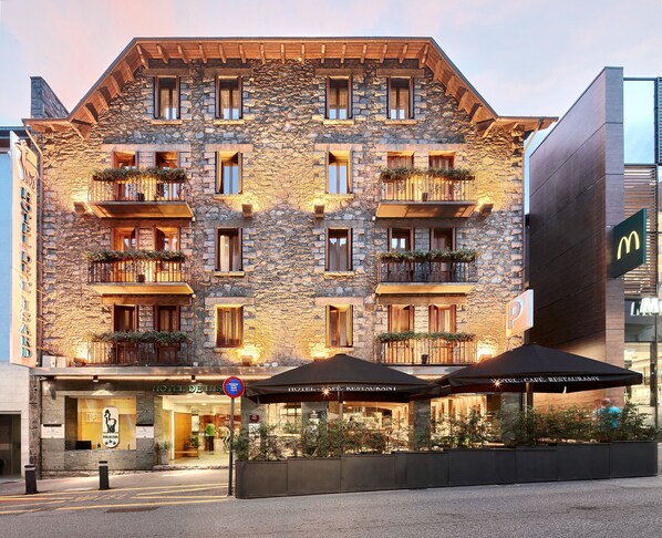 A stone building with multiple balconies, a McDonald's sign, and a hotel café restaurant. - Hotel de l'Isard (Andorra la Vella)