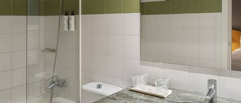A modern bathroom with a glass-enclosed shower, a white toilet, a sink with a granite countertop, and a large mirror.