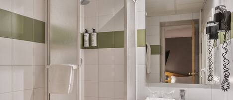 A bathroom with a shower, toilet, sink, and mirror.