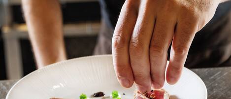 A chef placing a slice of meat on a plate.