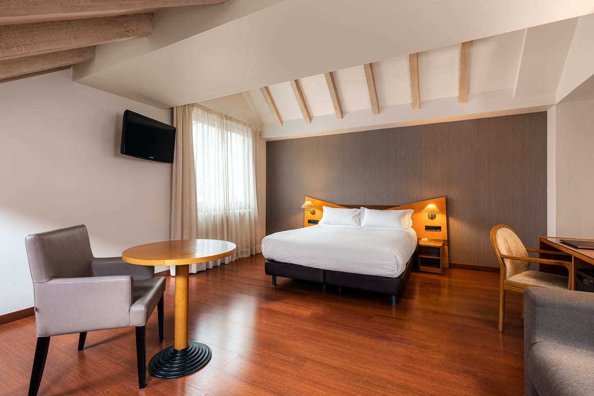 Ein modernes Hotelzimmer mit einem großen Bett, einem runden Tisch und zwei Stühlen.