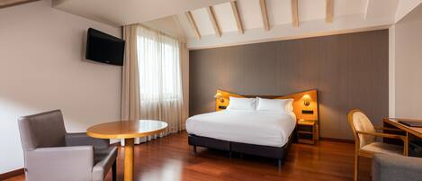 A modern hotel room with a large bed, a round table, and two chairs.