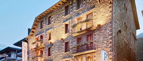 Un edificio de piedra con varios balcones, una cafetería y un restaurante.