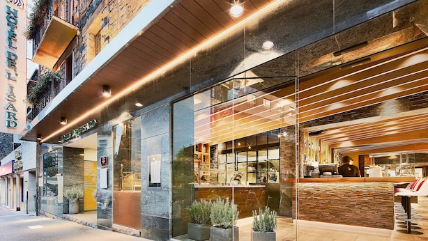 A hotel with a modern facade, large windows, and a reception area with a wooden counter. - Hotel de l'Isard (Andorra la Vella)