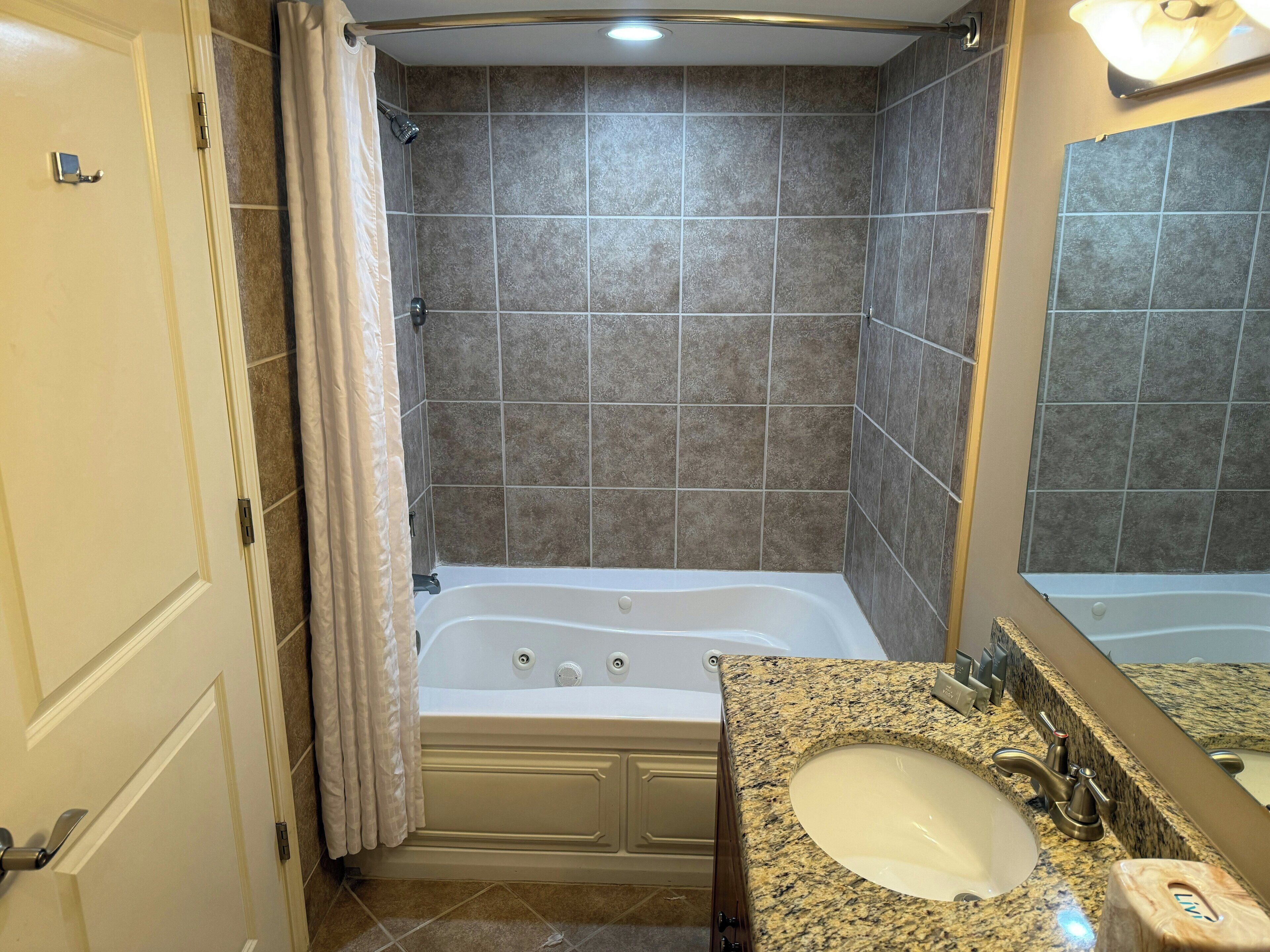 Un baño con bañera, lavamanos y espejo.