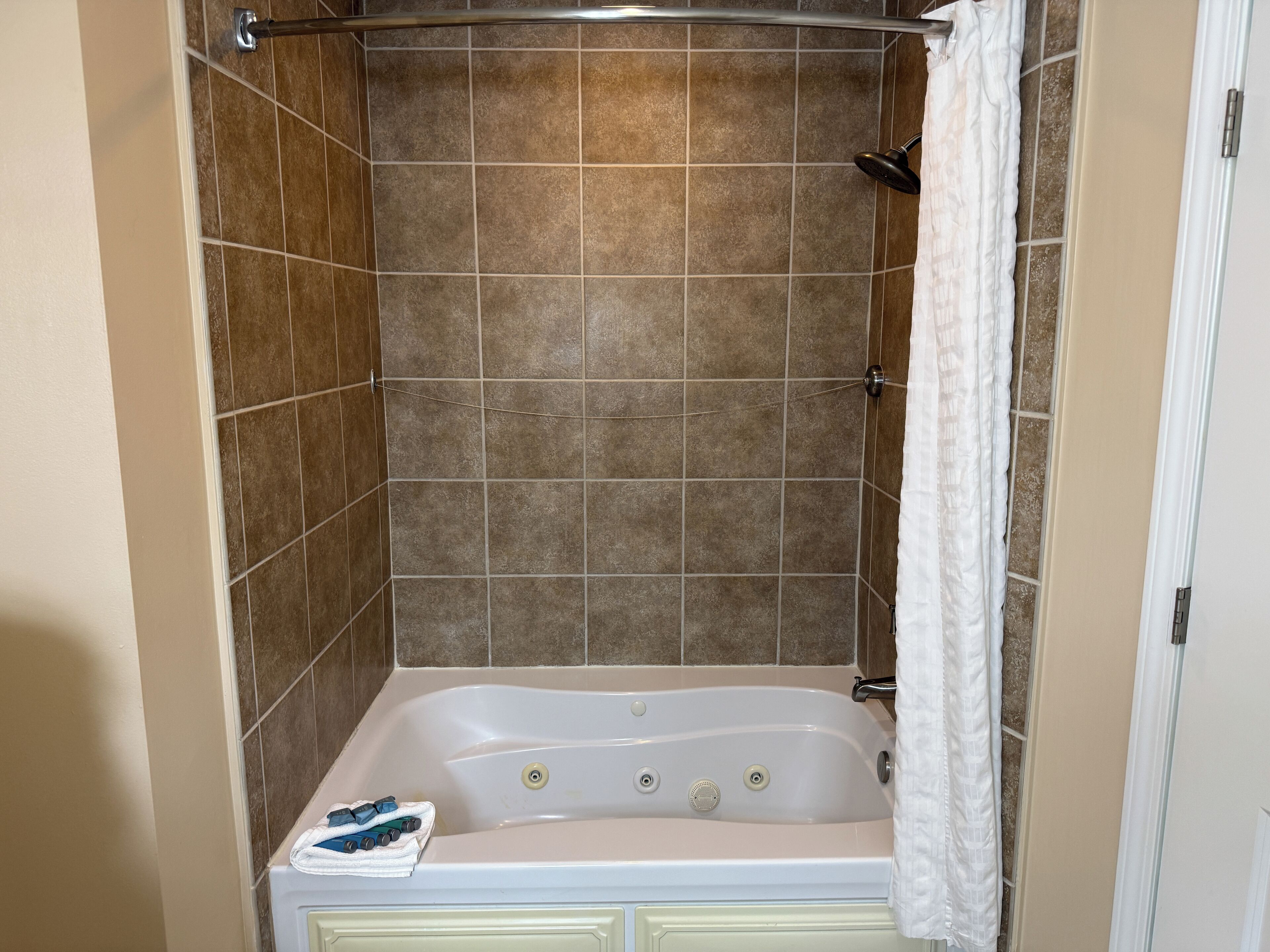 Une salle de bain avec une baignoire, des murs carrelés et un rideau de douche.
