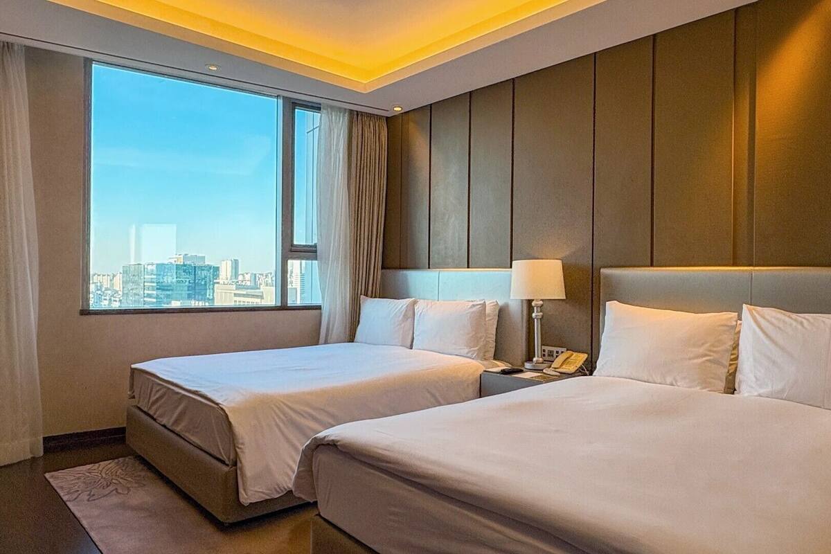 Habitación de hotel con dos camas, vistas a la ciudad y un diseño moderno.