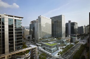 Un moderno paisaje urbano con edificios altos, incluyendo un edificio destacado con fachada de entramado y otro con techo verde distintivo.