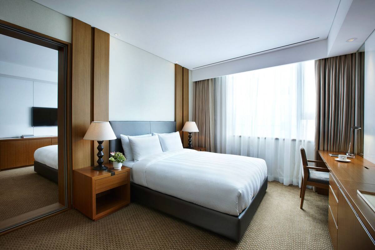 Een moderne hotelkamer met een groot bed, twee nachtkastjes met lampen, een bureau en een stoel.