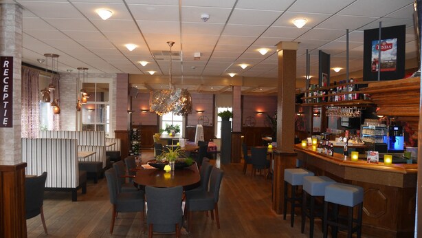 Een restaurant met een bar, houten vloeren en een kerstboom.
