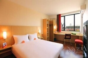 A hotel room with a large bed, a desk, a chair, and a window with a view. - Ibis Changchun Jianshe Street (Changchun)