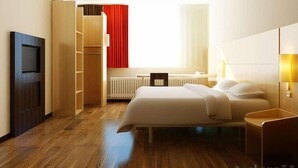 A hotel room with a bed, bedside table, TV, wardrobe, and a window with curtains. - Ibis Changchun Jianshe Street (Changchun)