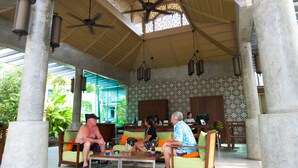 A covered outdoor seating area with steps leading up to it, featuring a ceiling fan, patterned wall tiles, and a view of the surrounding greenery. - Ramaburin Resort (Patong)