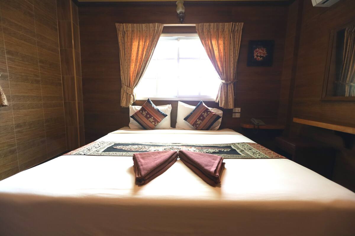 A hotel room with a large bed, curtains, a window, and a framed picture on the wall.