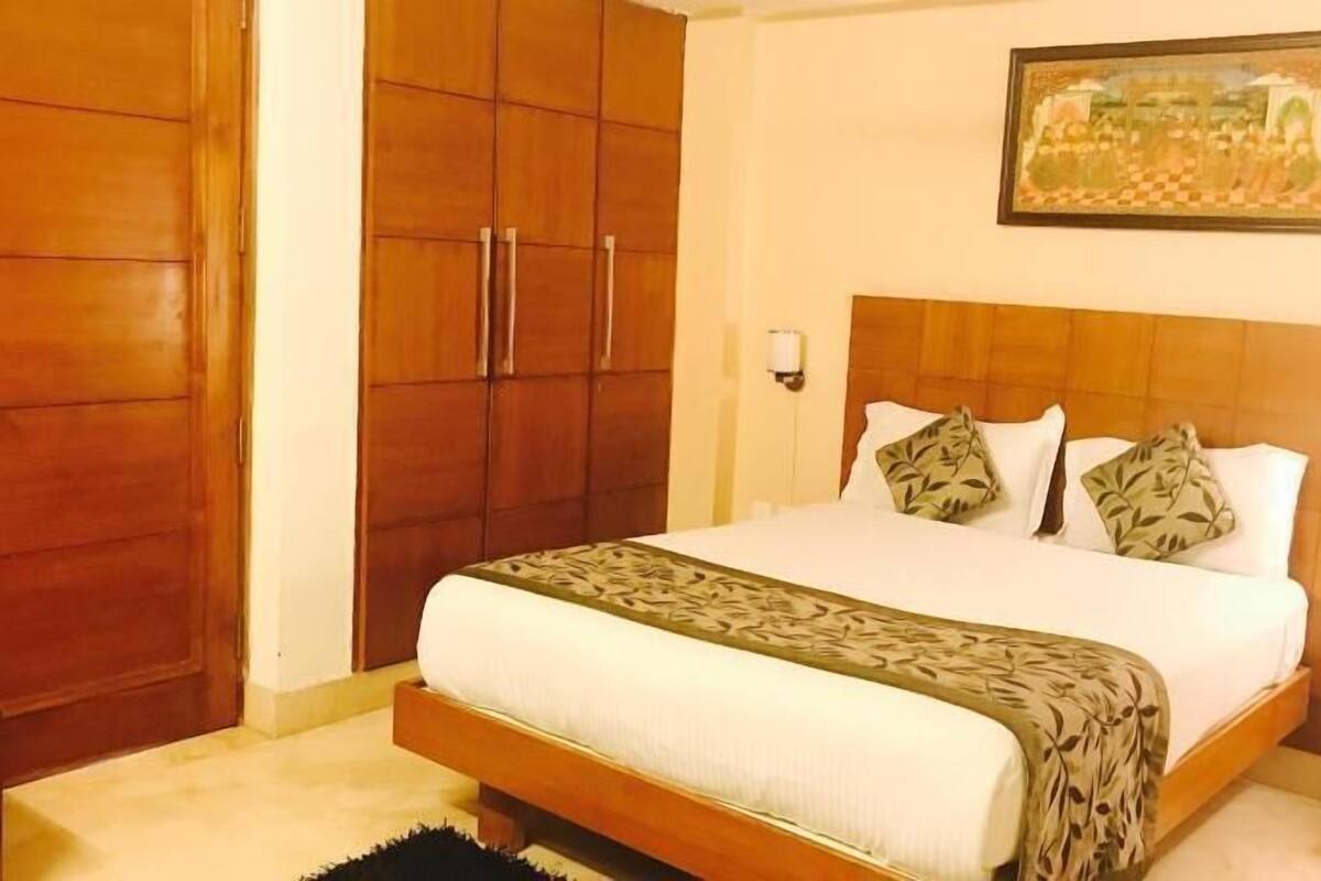 Un dormitorio con cama, armario de madera y un cuadro en la pared.