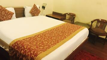 Une chambre d’hôtel avec un grand lit, une table de chevet en bois, une chaise et un tapis rouge.