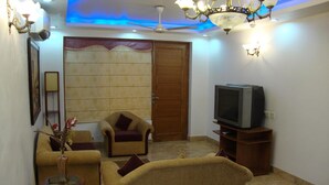 Una sala de estar con un sofá, un sillón y un televisor sobre un mueble de madera.