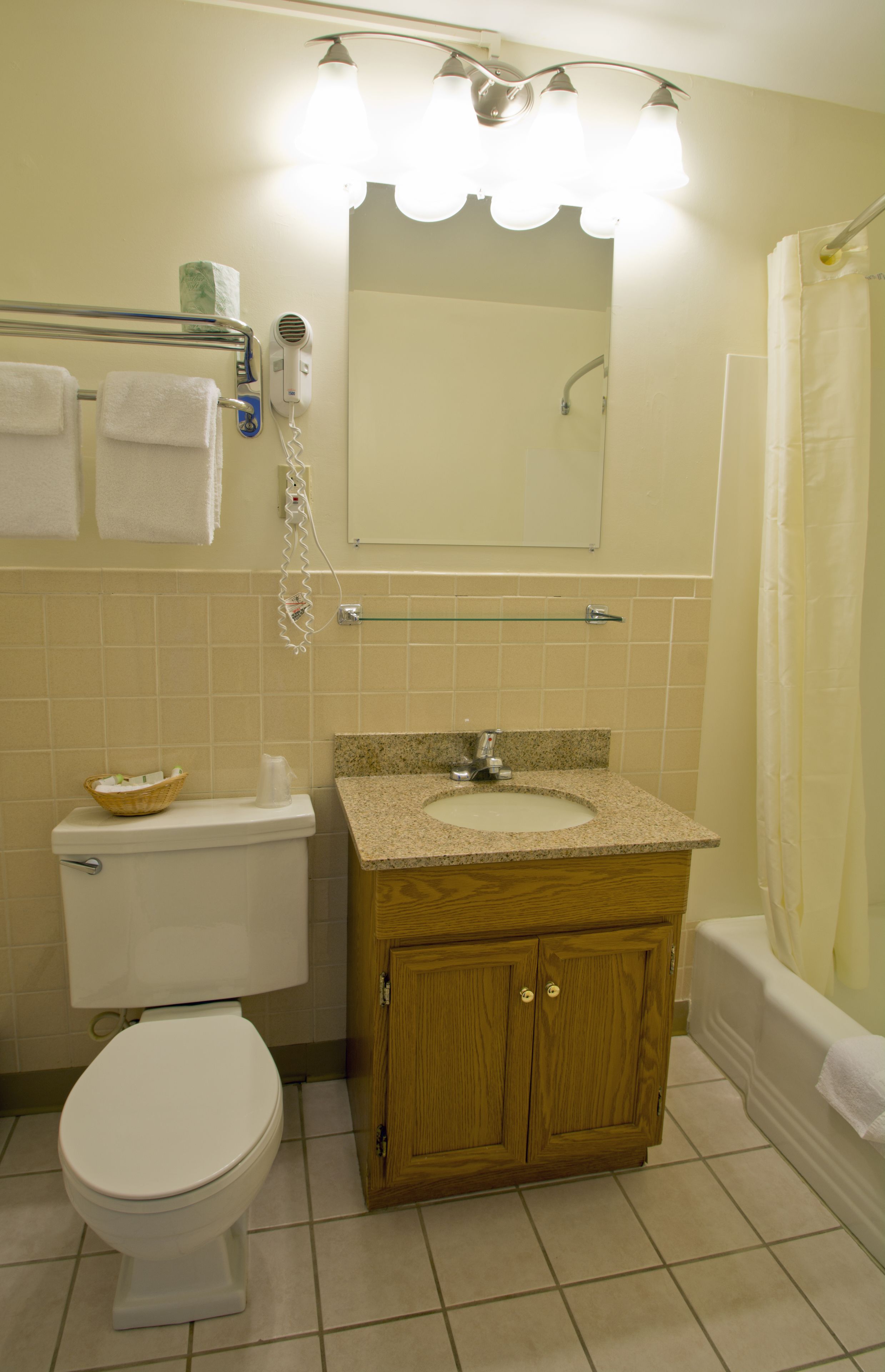A bathroom with a toilet, sink, mirror, and shower curtain.
