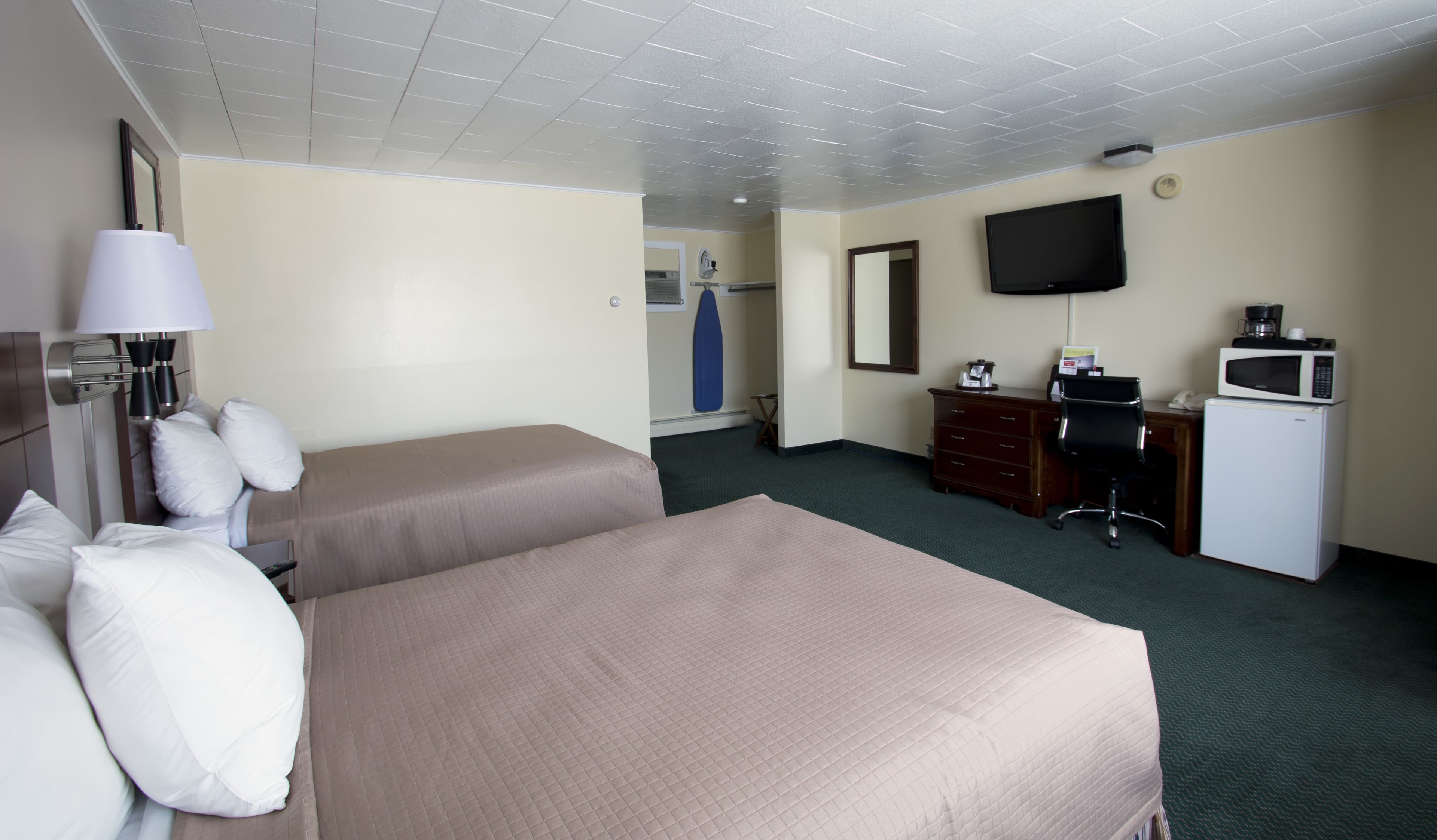 A hotel room with two beds, a desk, a television, and a microwave.