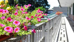 A balcony with potted flowers and a tiled floor. - Travelers Inn (Brunswick)