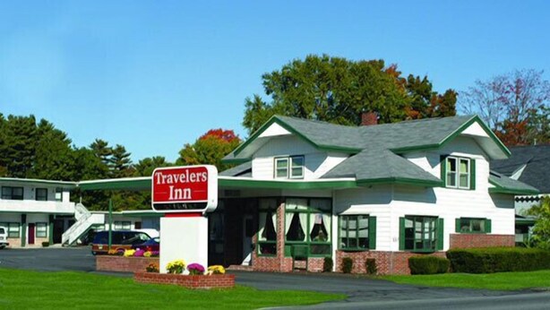 A Travelers Inn with a white exterior, green trim, and a prominent sign. - Travelers Inn (Brunswick)