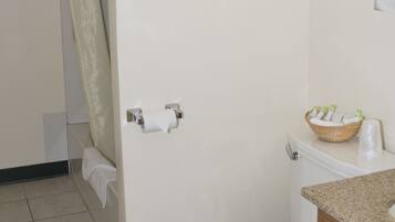 A bathroom with a toilet, a sink with a wooden cabinet, and a shower curtain.