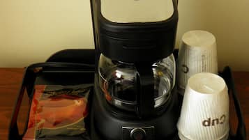 A coffee maker with a coffee pod, a white mug, and a glass carafe on a tray.
