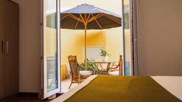 A room with a sliding glass door leading to an outdoor area with a table, chairs, and an umbrella.