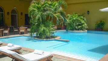 A pool area with lounge chairs and potted plants.