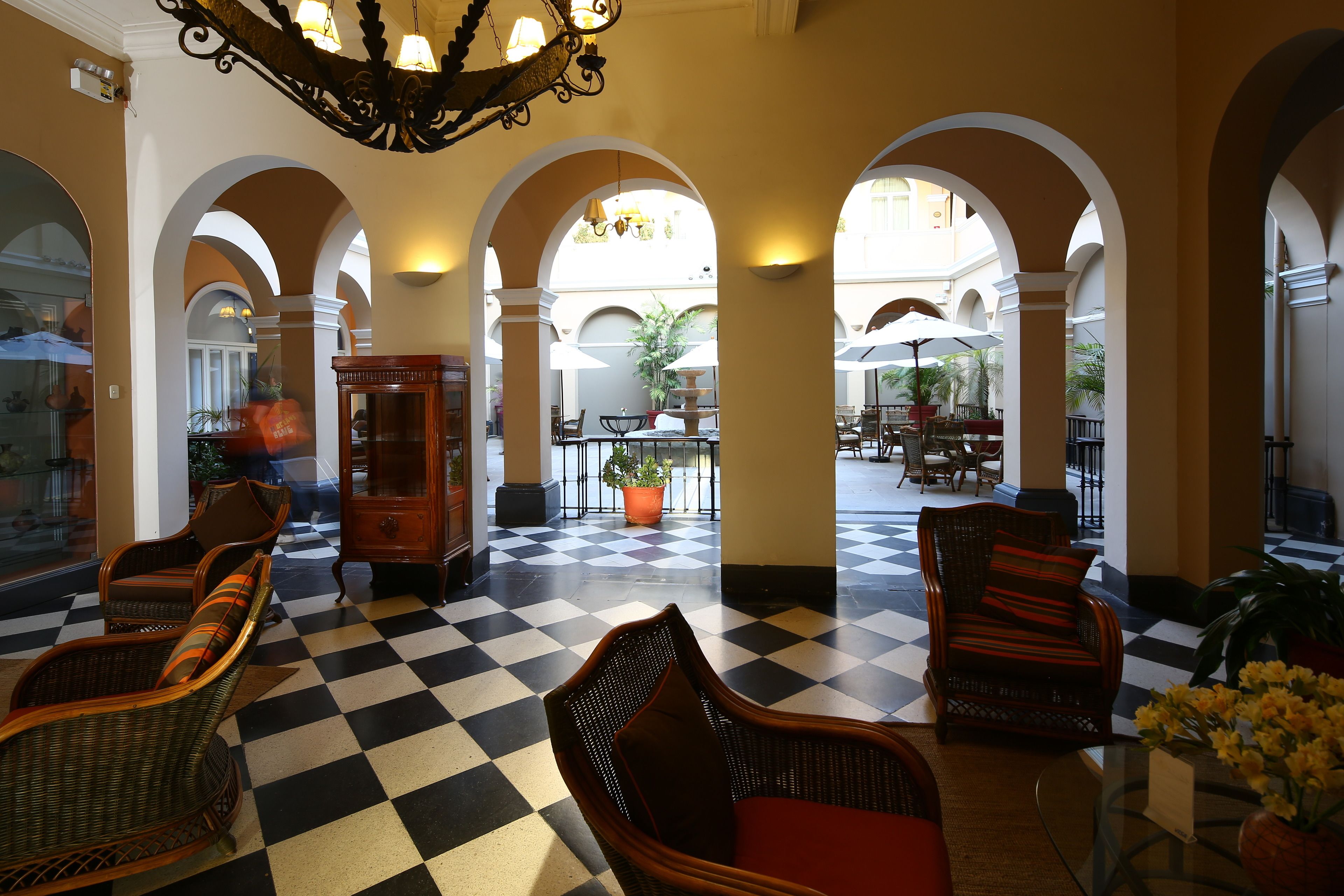 A lobby with checkered flooring, wicker furniture, and a view of an outdoor patio area.