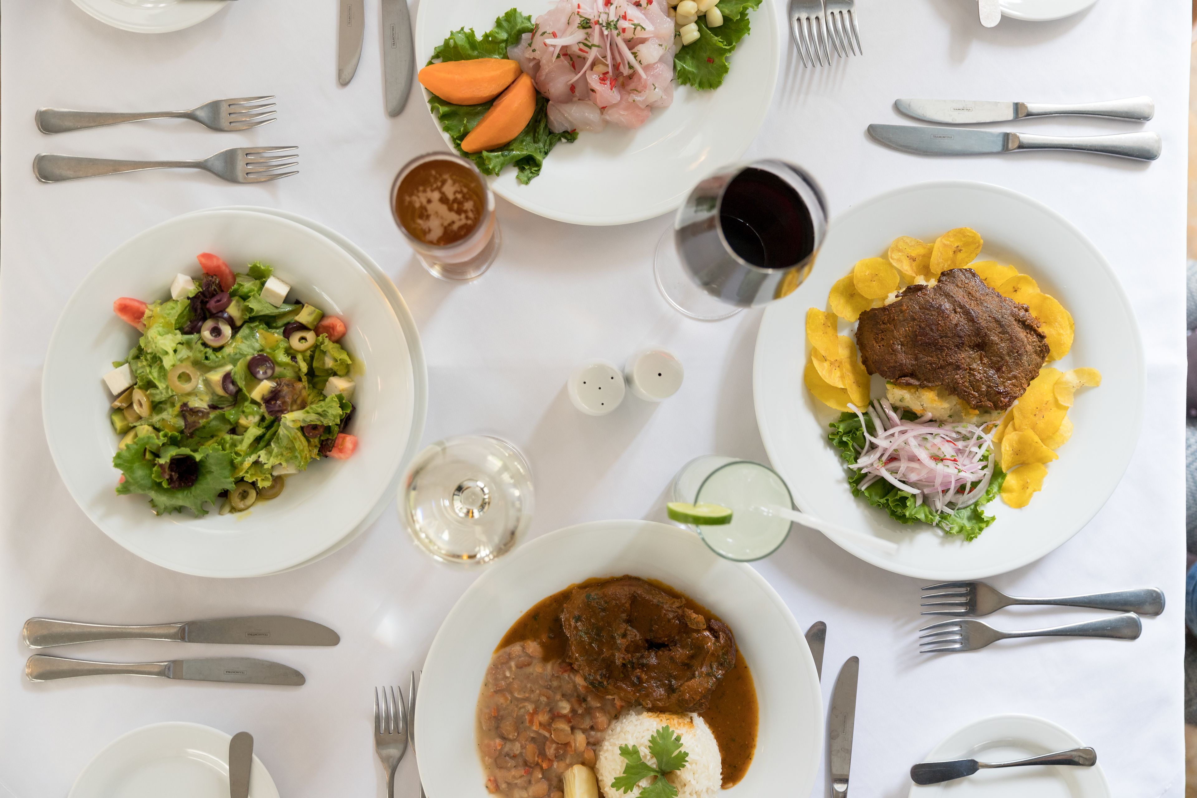 A dining table with various dishes, utensils, and condiments.