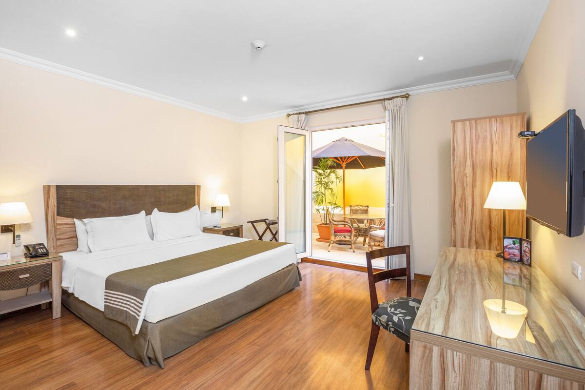 Une chambre d’hôtel avec un grand lit, des tables de chevet, un bureau et une télévision.
