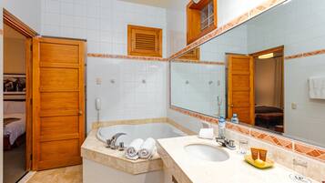 A bathroom with a bathtub, two sinks, a large mirror, and a wooden door.