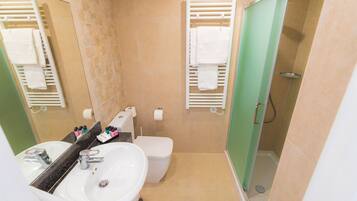 A bathroom with a sink, toilet, and shower. There are towels hanging on towel racks.