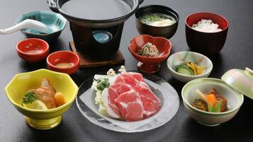 Une variété de plats et un ensemble pour préparer une fondue chinoise sont disposés sur une table.