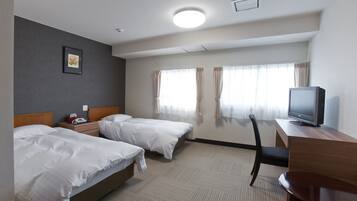 A hotel room with two beds, a desk with a television, and a chair.