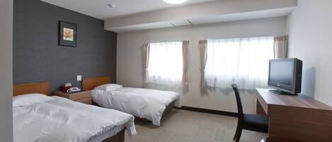 A hotel room with two beds, a desk with a television, and a chair.