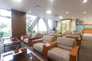 Een moderne hotellobby met comfortabele zitplaatsen, grote ramen en een receptie.