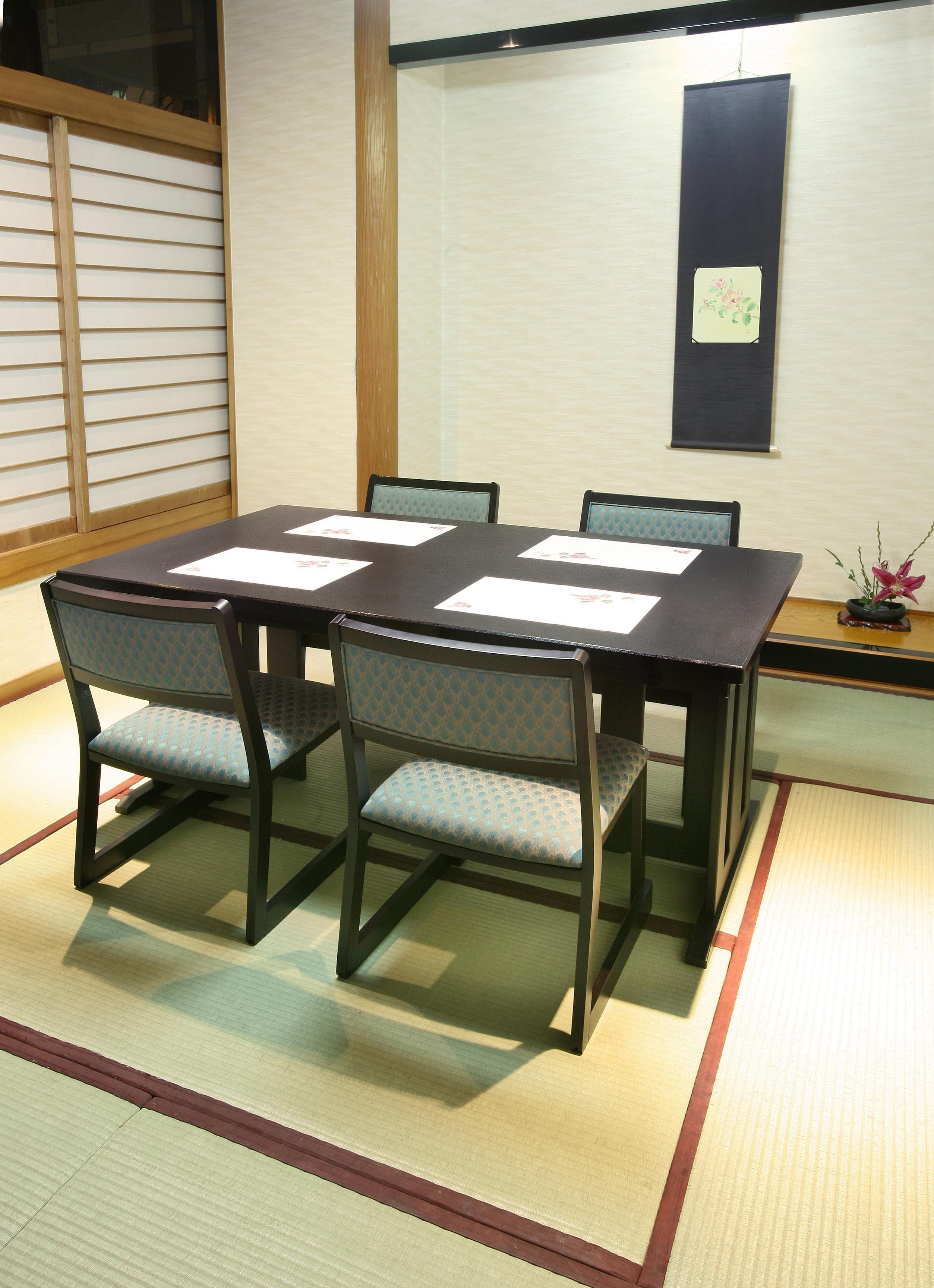 A traditional Japanese-style meeting room with tatami flooring, a low table, and matching chairs.