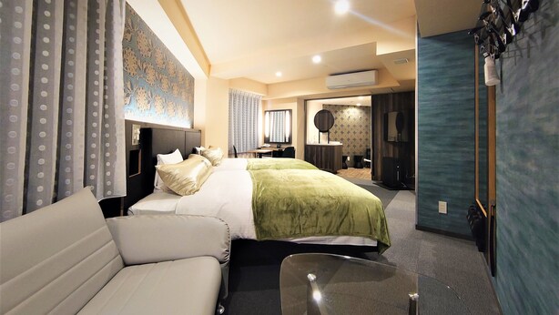 A hotel room with two beds, a sofa, a desk, and a TV.