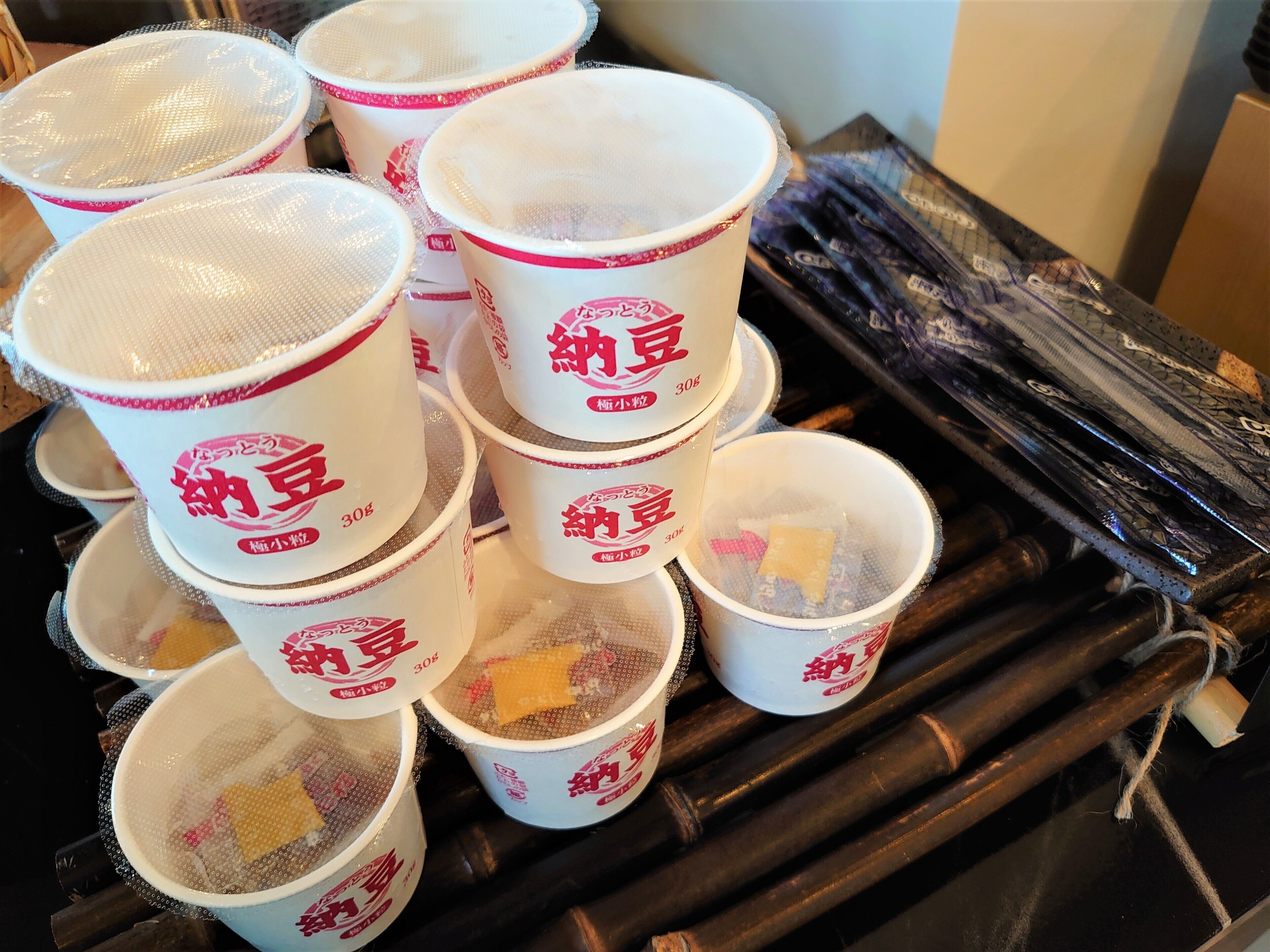 A stack of white cups with red text and a mesh lid, placed on a wooden surface.