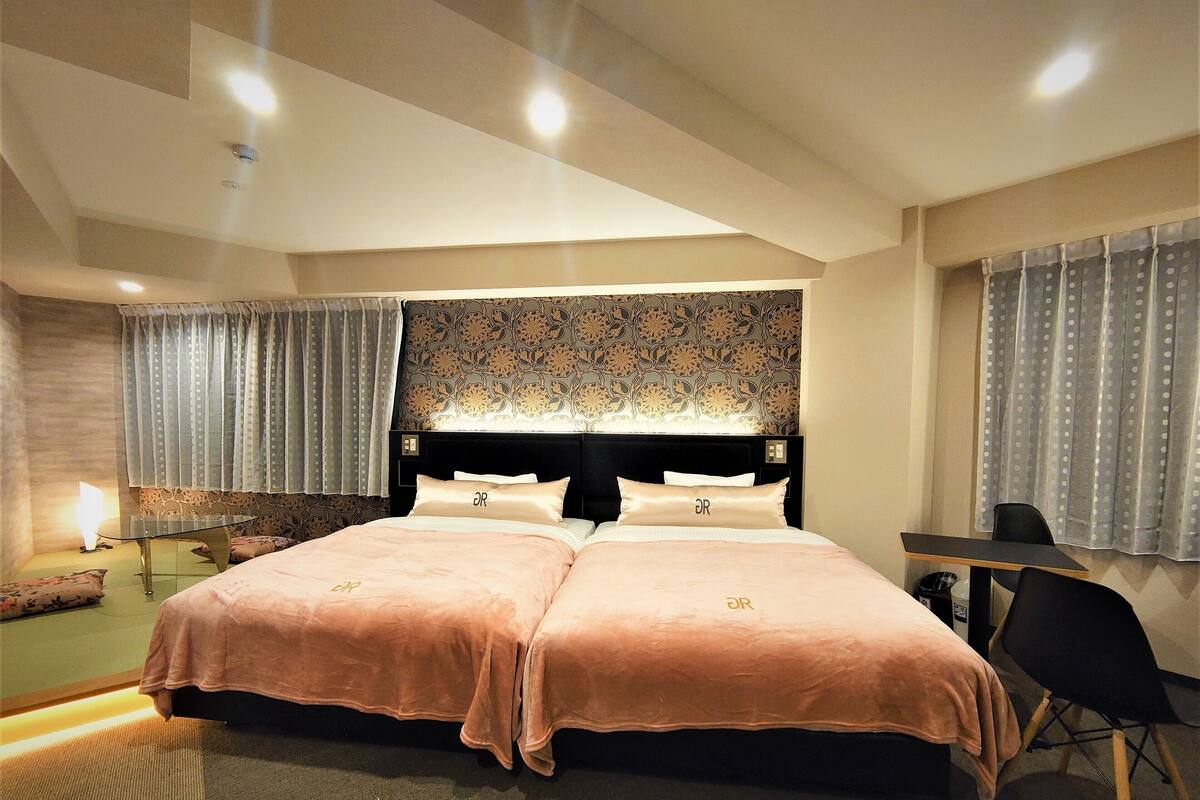 A double bed with matching headboards, a desk, and a chair in a hotel room.