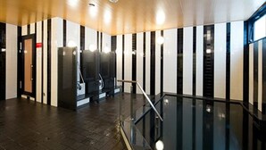 A modern interior with a glass staircase, black and white striped walls, and a polished floor.