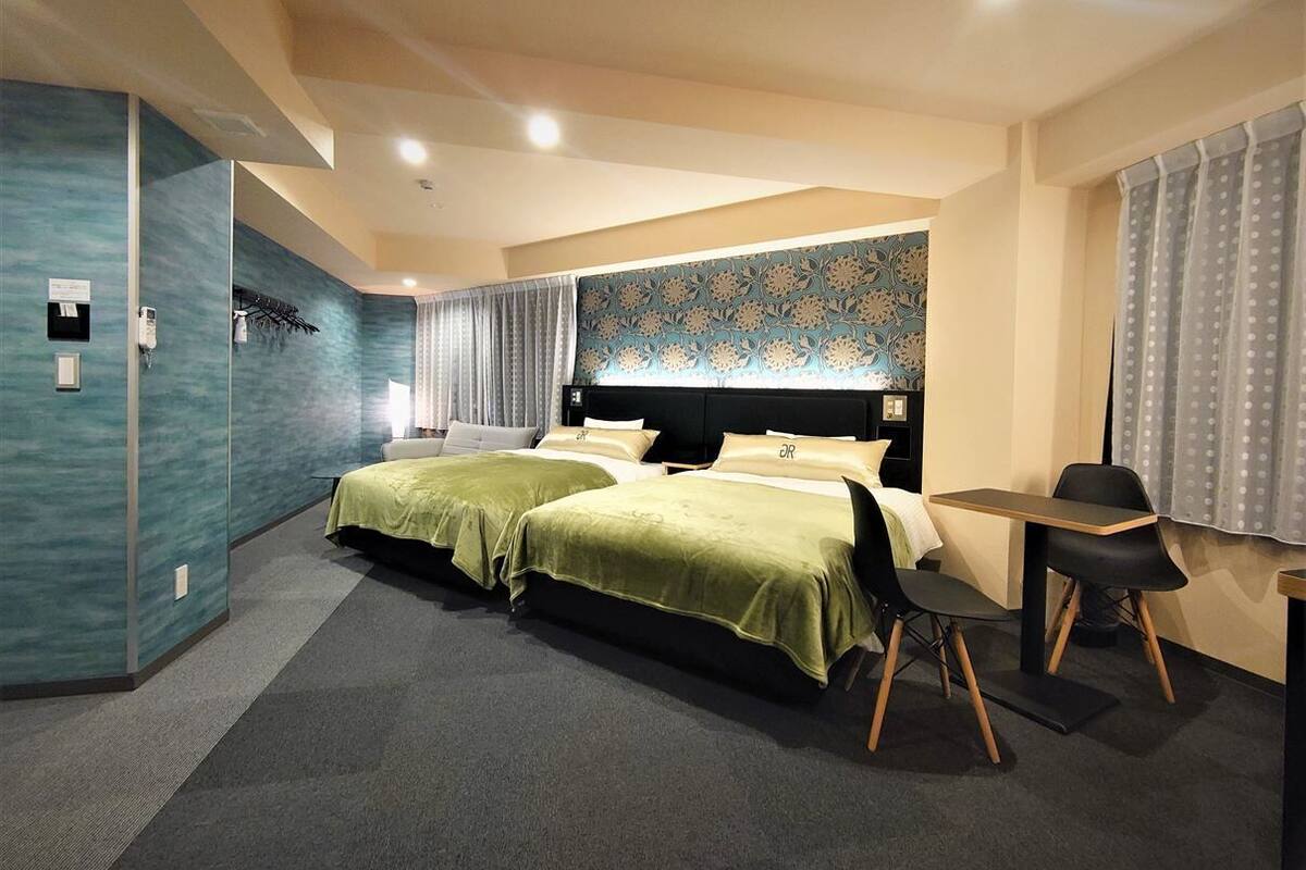 A hotel room with two beds, a desk, and a chair.