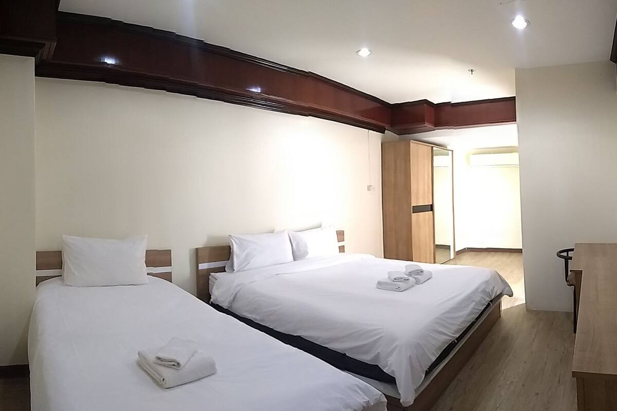A hotel room with two beds, a wooden desk, and a mirror.
