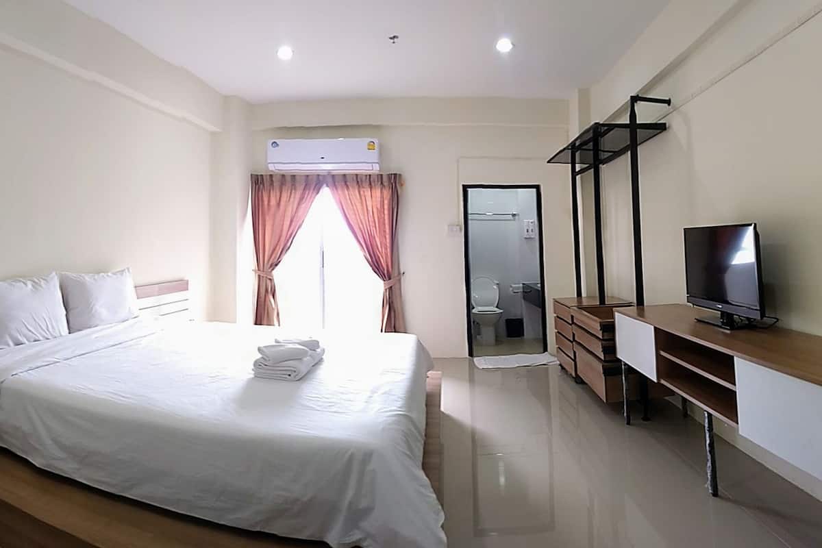 A hotel room with a bed, a TV, a desk, and a bathroom.