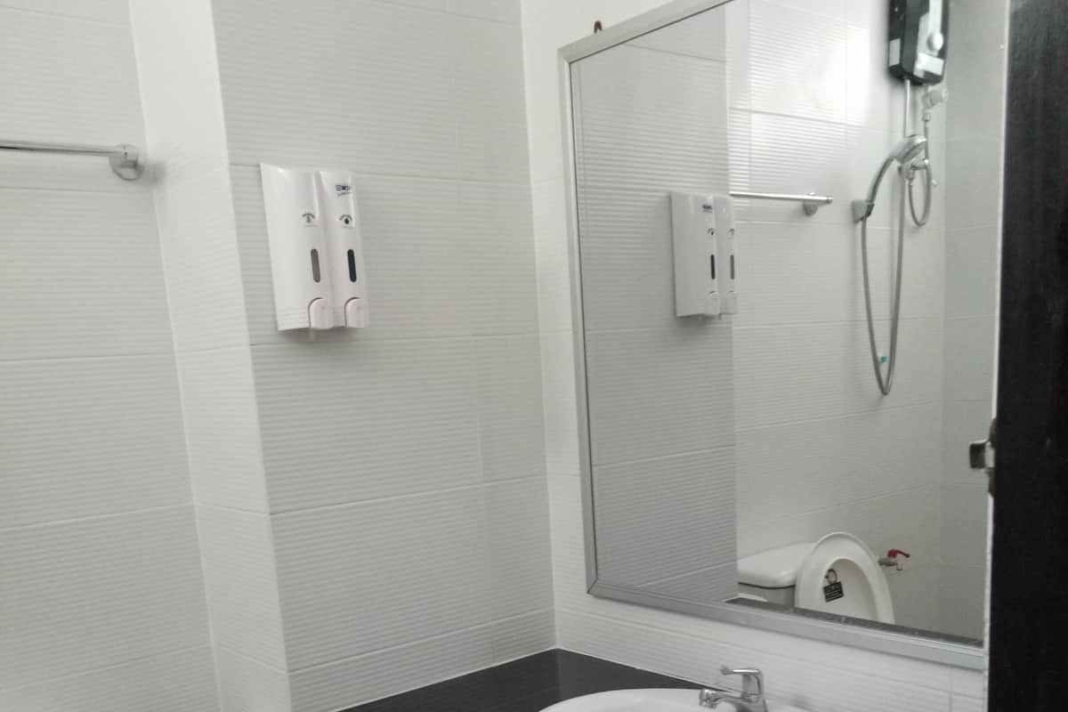A modern bathroom with a white toilet, a black sink, and a large mirror.