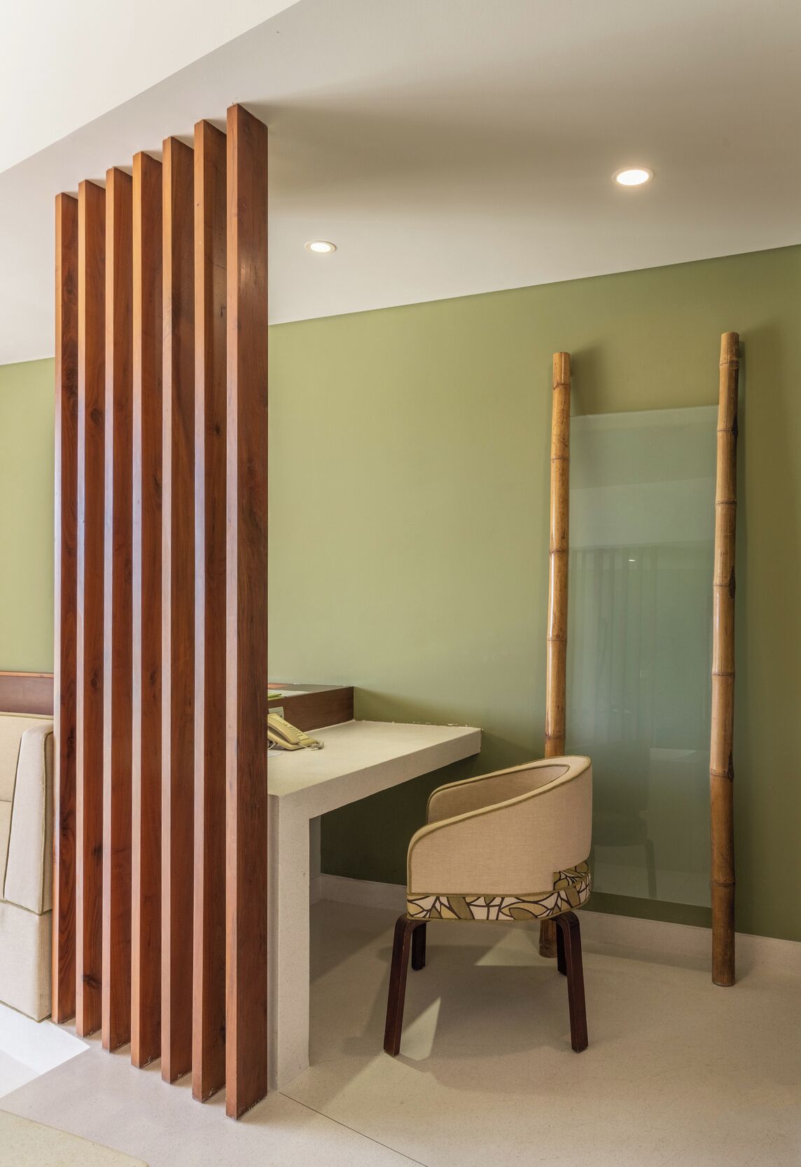 Een moderne kamer met een houten scheidingswand, een glazen douche en een stoel.