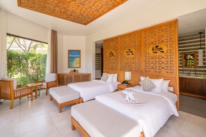 Habitación de hotel con dos camas, cabecero de madera, escritorio y vista a zonas verdes.