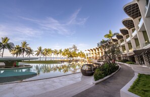 Un resort con piscina, palmeras y arquitectura moderna.